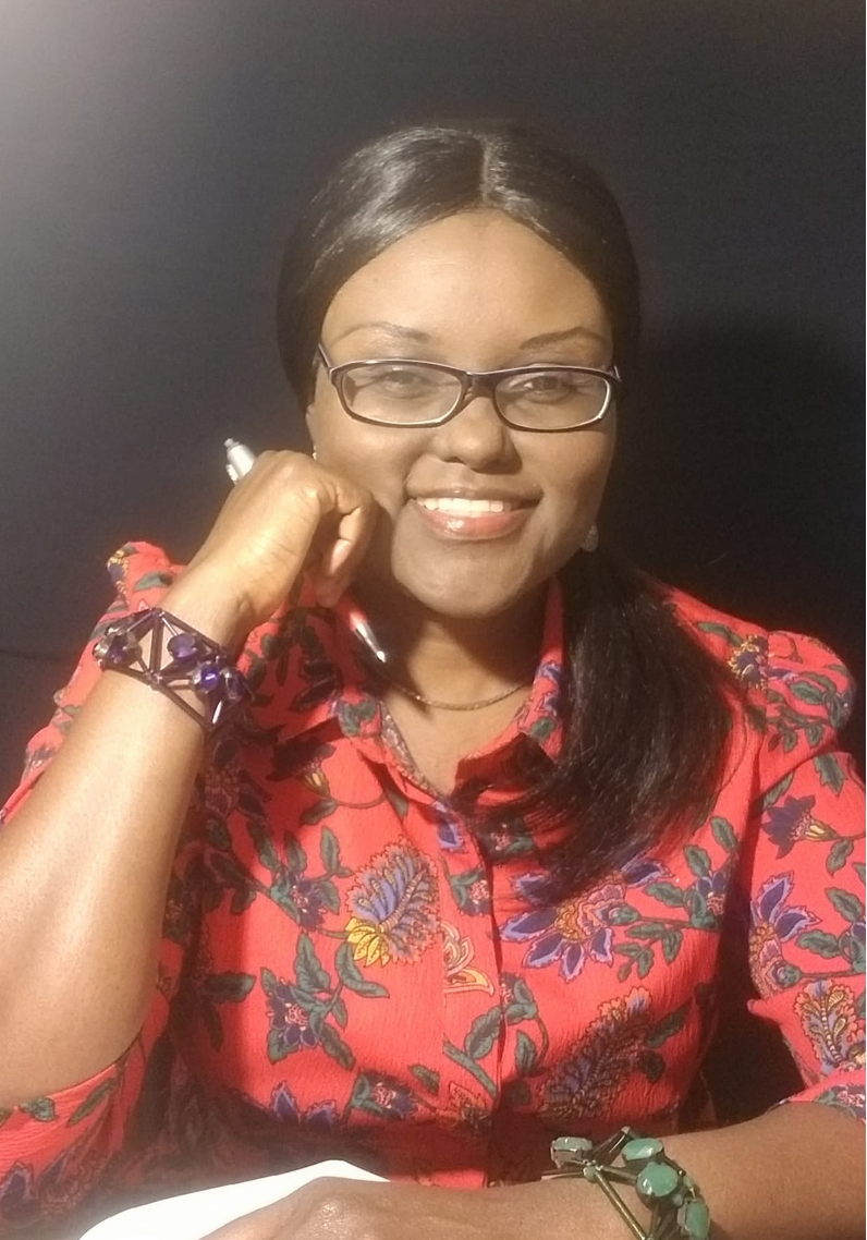Woman with glasses and a brightly colored shirt smiles at camera.
