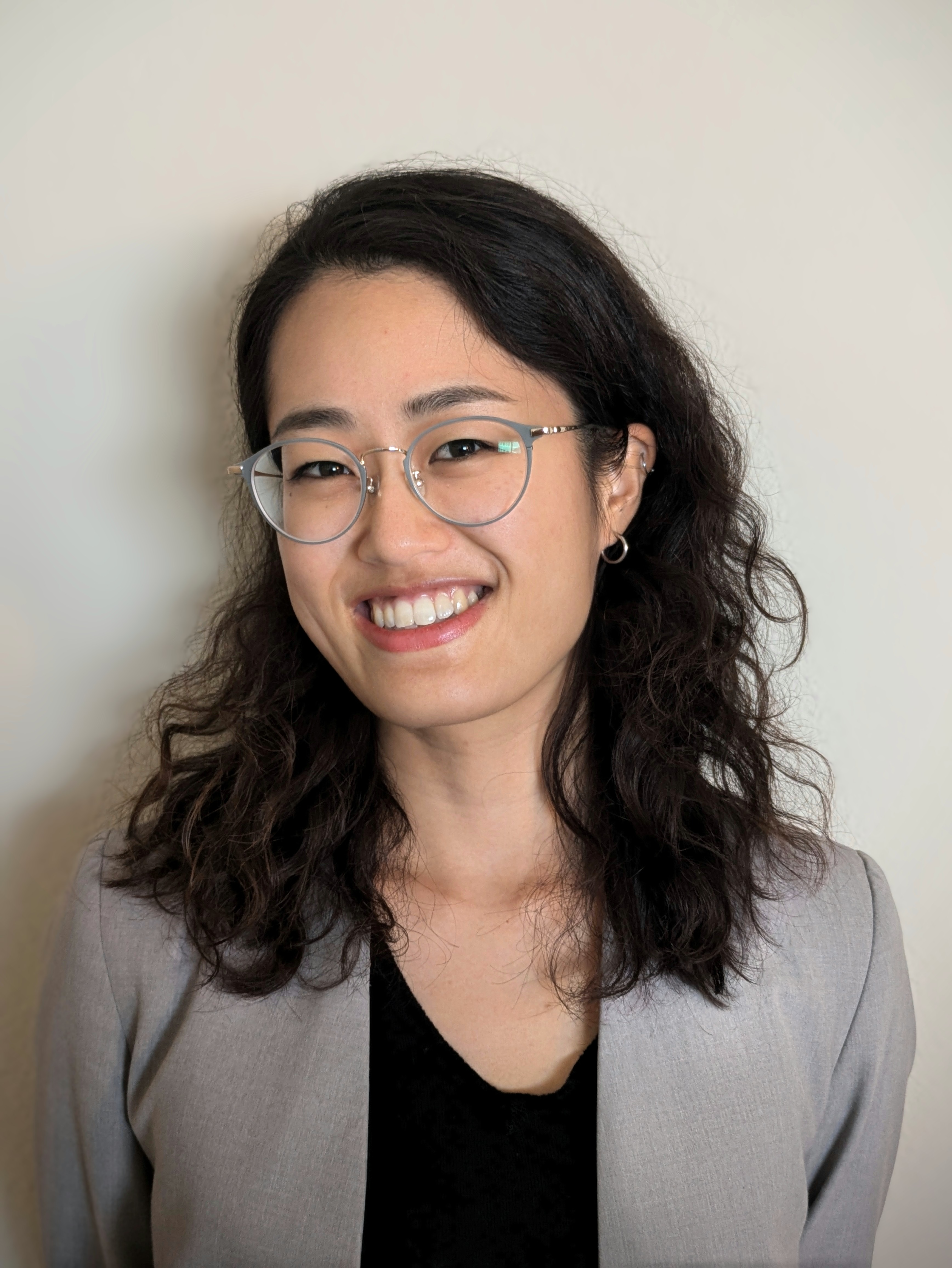 Woman in glasses with shoulder-length hair smiles at camera